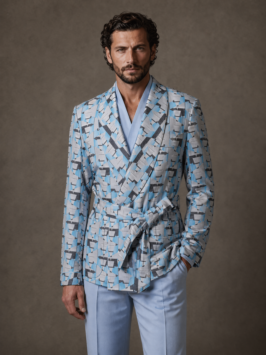 Full-length studio photograph of the Vittorio Light Blue Geometric Belted Shawl Collar Jacket, a made-to-order men's belted shawl-collar statement jacket in a lightweight fluid cloth with a light blue and grey abstract geometric print, tailored to your measurements for evenings, parties, and galas and shipped nationwide by Zane.