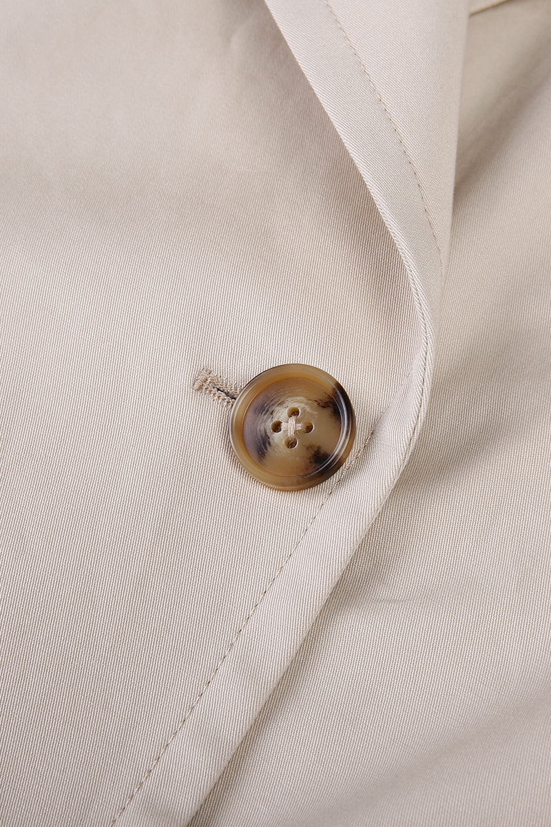 Close-up of a button on a beige fabric surface custom made suits for women