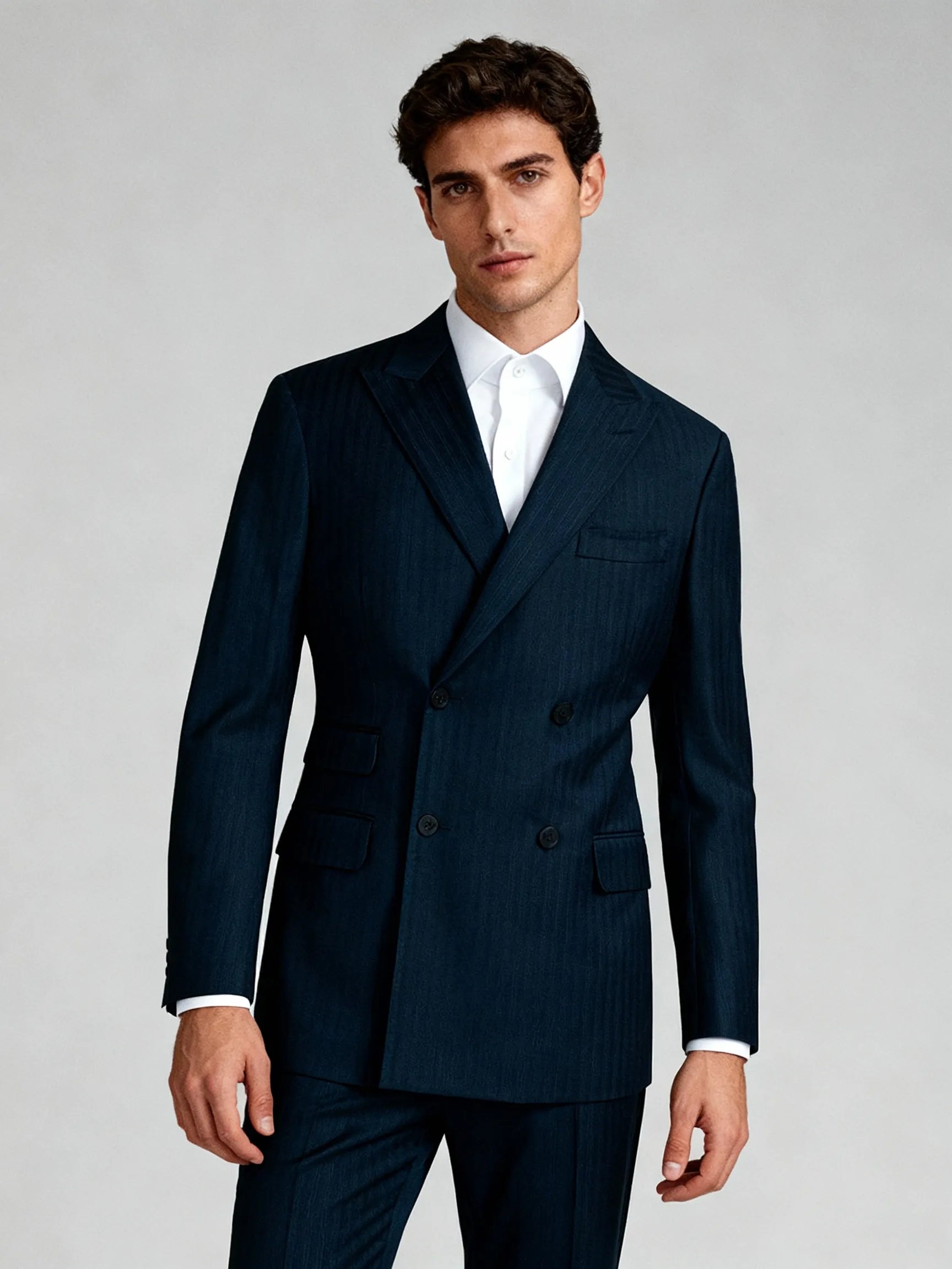 Man wearing a navy pinstripe suit on a gray background custom suits near me