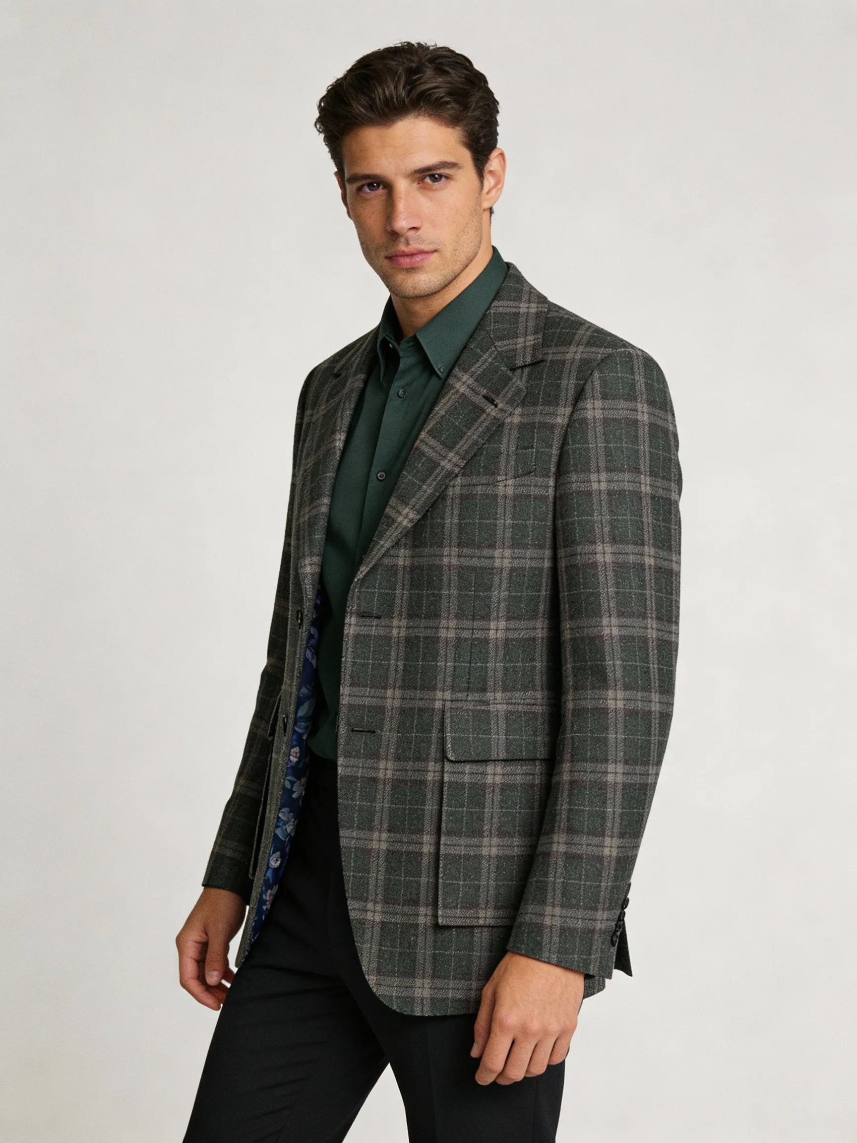 Man wearing a plaid blazer over a green shirt on a white background