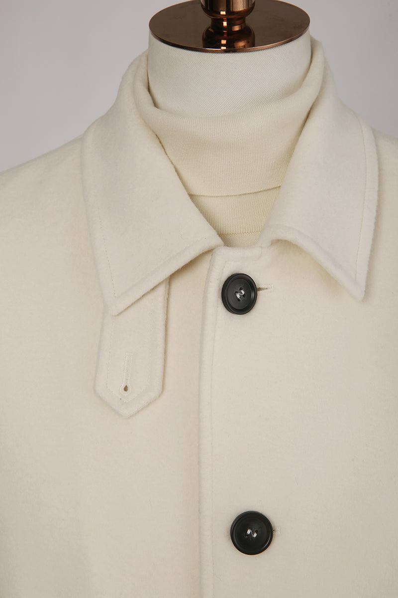 Close-up of a cream-colored coat with black buttons on a mannequin against a white background