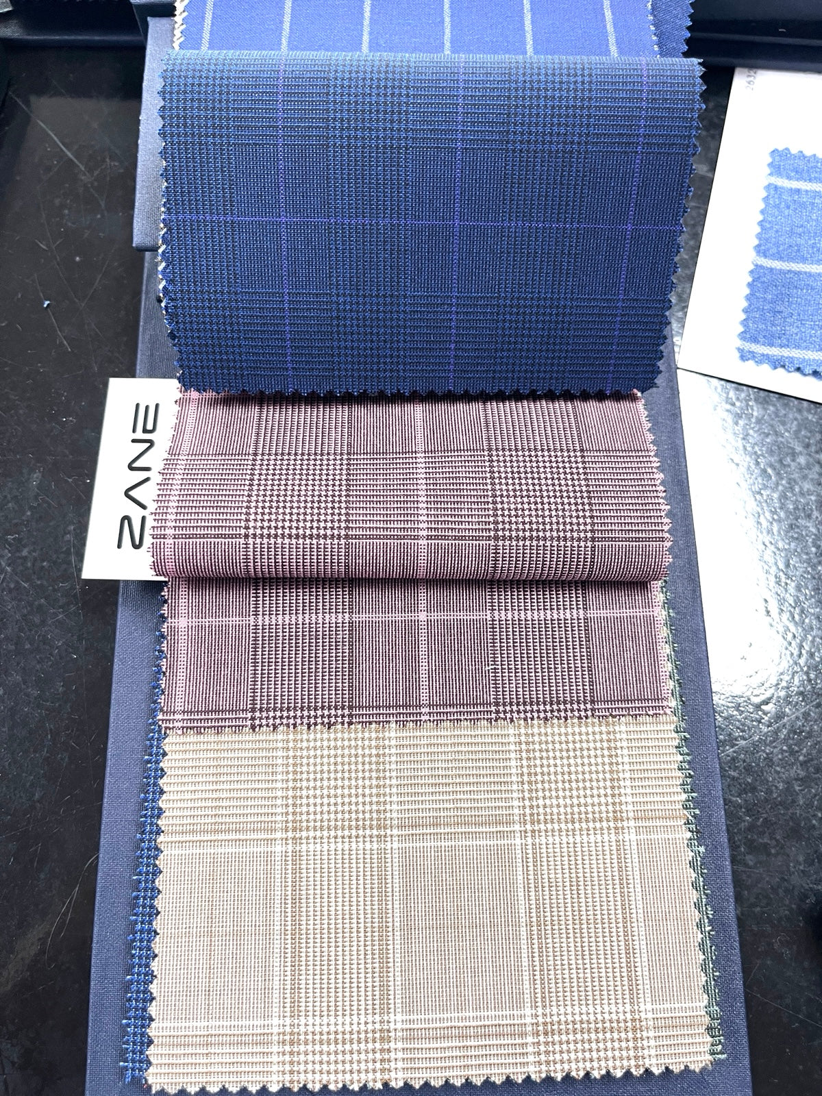 Suit fabric swatches Jacksonville Zane showing lightweight plaid fabrics in blue beige and brown used for custom suits and sport coats in Jacksonville Florida