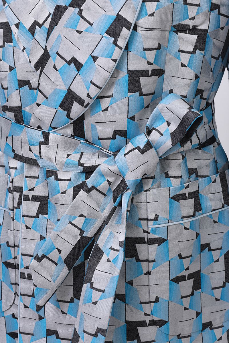 Fabric and print close-up of the Vittorio Light Blue Geometric Belted Jacket, showing the lightweight fluid cloth with a light blue and grey abstract geometric pattern, made to order and shipped nationwide by Zane.