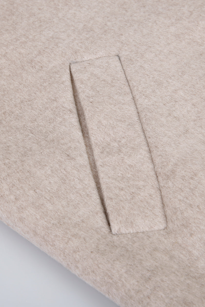 Close-up of a beige fabric with a rectangular pocket detail on a light gray background
