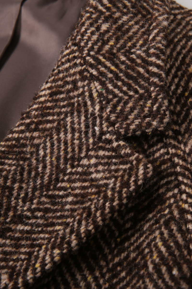 Close-up of a brown and beige herringbone patterned fabric. custom made online suits 