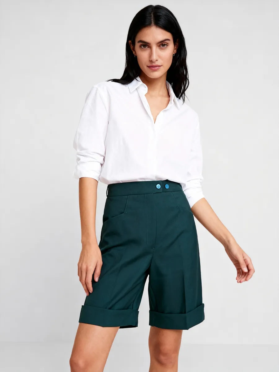 Woman wearing a white blouse and green shorts on a plain background