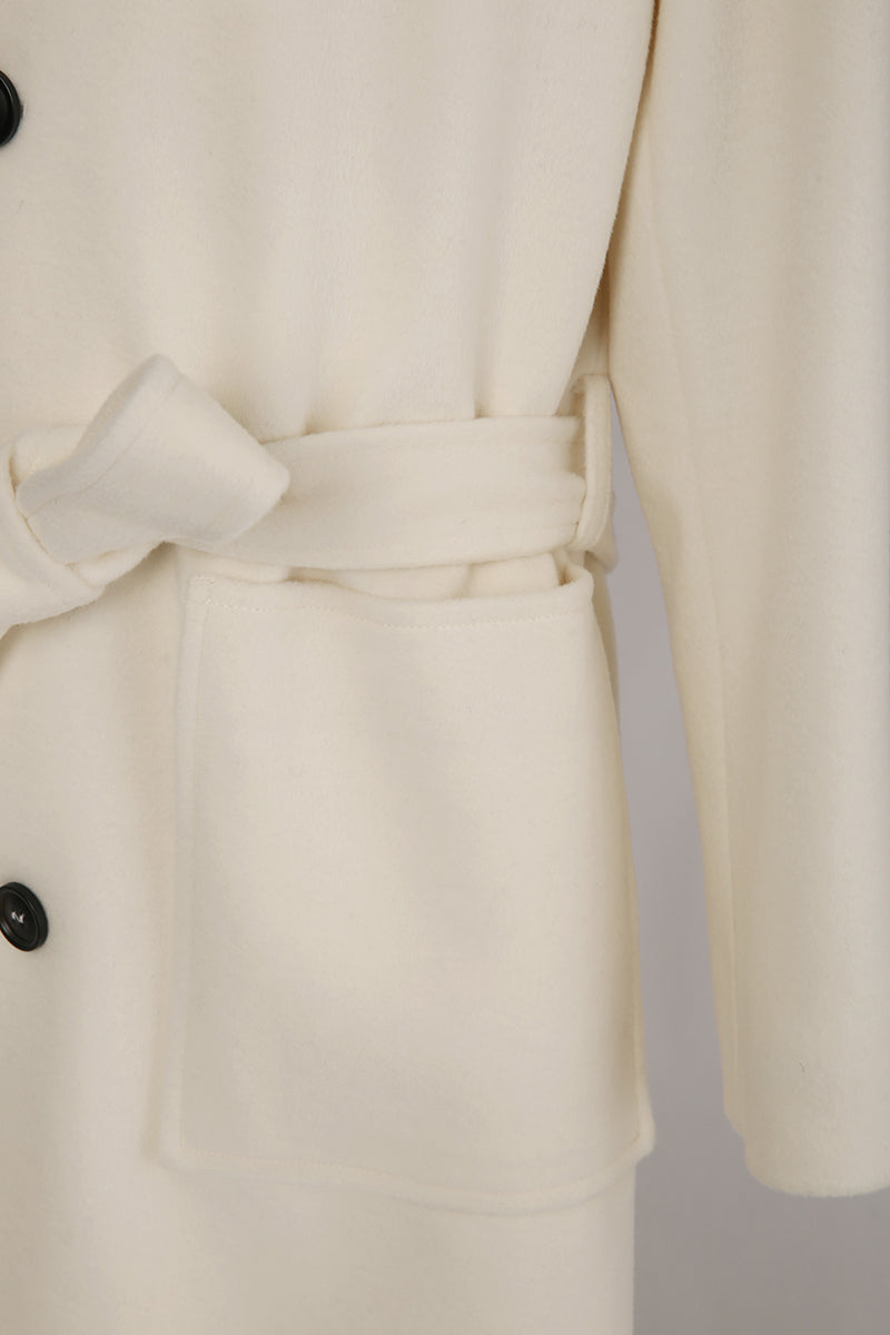 Close-up of a cream-colored coat with a belt and button details on a light gray background